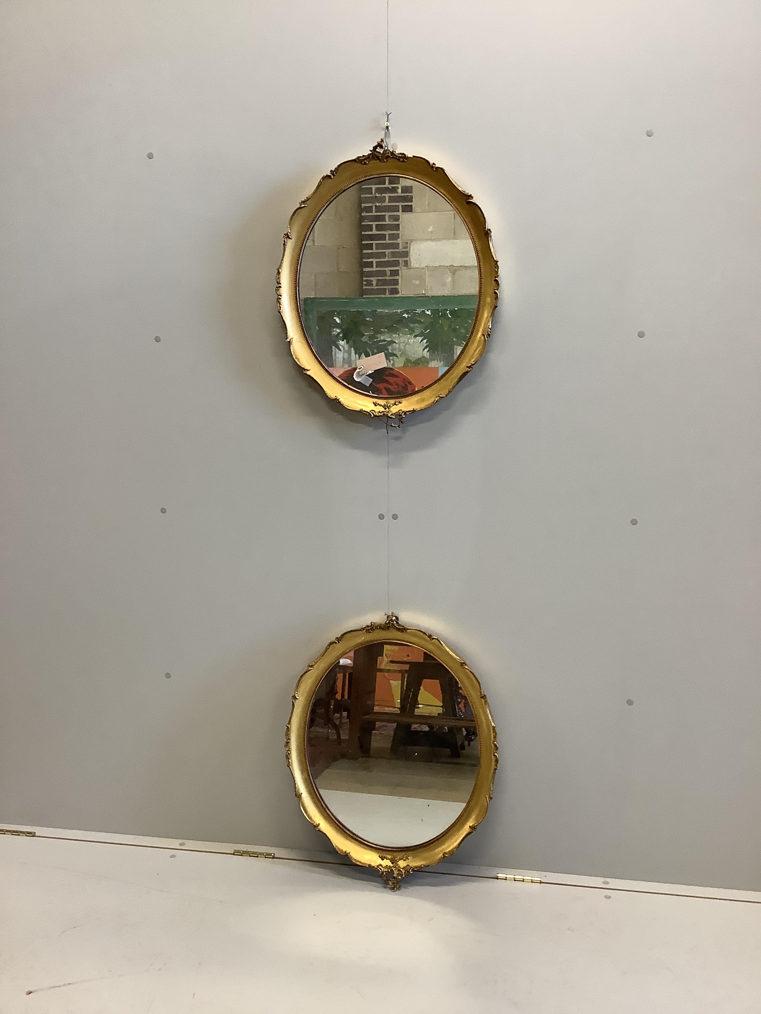 A pair of early 20th century oval giltwood and composition wall mirrors, width 53cm, height 67cm